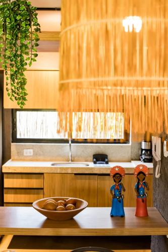 deux figurines sur un comptoir de cuisine avec un bol de fruits dans l'établissement Casa Vilas Patacho Garden, à Porto de Pedras