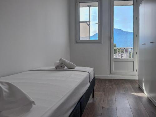 ein weißes Schlafzimmer mit einem Bett und einem Fenster in der Unterkunft Le Second Verderet in Grenoble