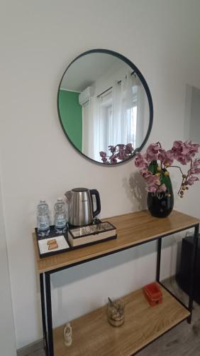 a table with a mirror and a vase with flowers on it at Donna Giovanna Guest House in Cosenza