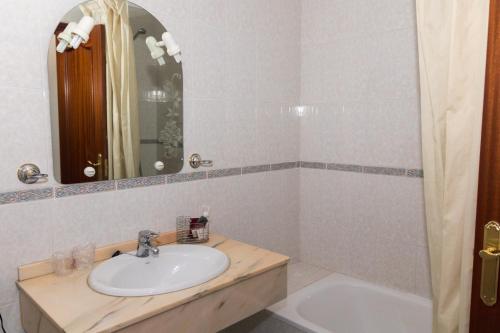 a bathroom with a sink and a mirror and a tub at Hotel Avenida III in Villadangos del Páramo