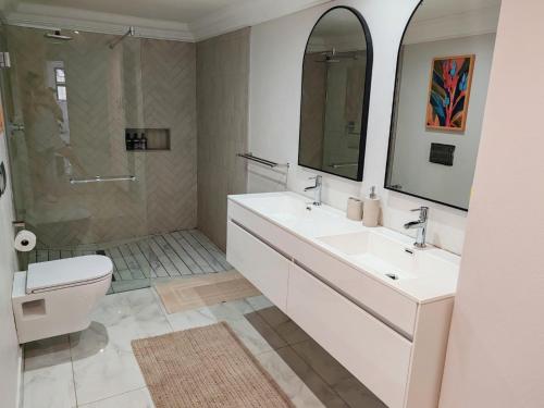 a bathroom with two sinks and a shower and a toilet at Mtunzini South Cottage in Mtunzini