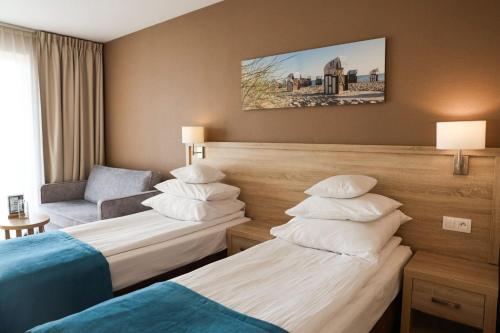 Tristan Hotel & SPA في كيتي ريباكي: غرفة فندقية بسريرين وكرسي