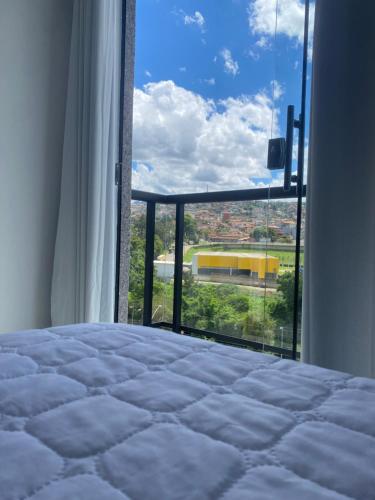 ein Schlafzimmer mit einem Bett und einem großen Fenster in der Unterkunft Apartamento em Mariana in Mariana
