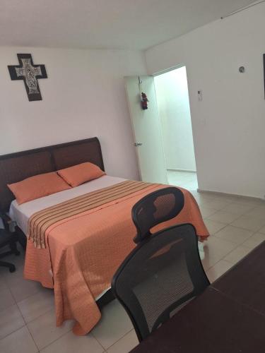 a bedroom with a bed with an orange blanket and a chair at Comfortable and nice house in Caucel in Mérida