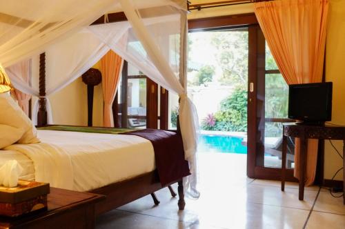 a bedroom with a bed and a tv and a pool at Villa Kamboja Golden Villa no2 in Sanur