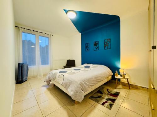 ein Schlafzimmer mit einem großen Bett mit einer blauen Wand in der Unterkunft Beauséjour in Saint-Herblain