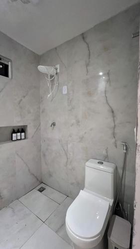 a bathroom with a white toilet and a marble wall at Apt 424 in João Pessoa