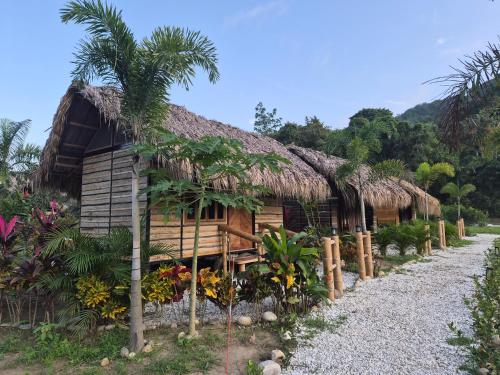una casa con tetto di paglia e una strada sterrata di Dos Peladas Hostal a Santa Marta