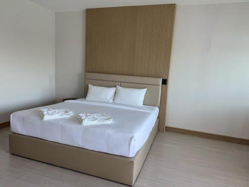 un lit avec des draps blancs et des oreillers dans une chambre dans l'établissement Madee House - มาดีเฮ้าส์, 
