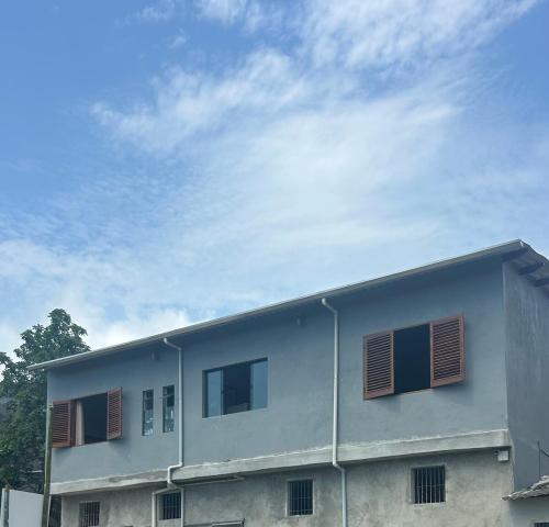 un bâtiment aux fenêtres à volets bruns et un ciel nuageux dans l'établissement Casa da Barra, à Ubatuba