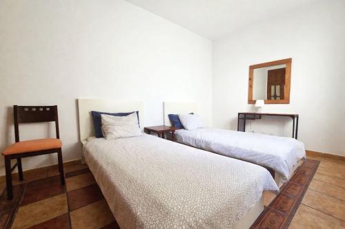 two beds in a room with a chair and a mirror at Famara Chill House in Famara