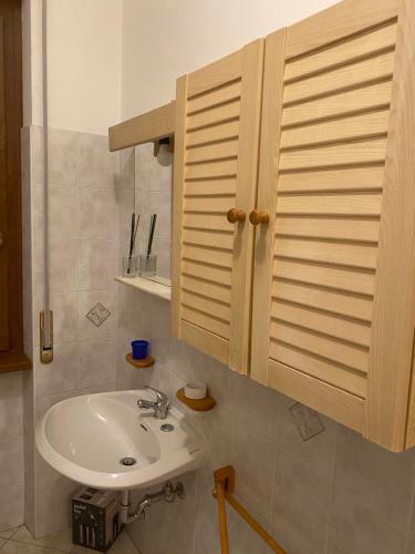 een badkamer met een wastafel en een houten kast bij Tamagno Residence - Comfort in the Heart of the City in Varese