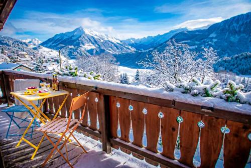 una mesa y sillas en un balcón con montañas cubiertas de nieve en Chalet 4 personnes avec sauna, en Leysin