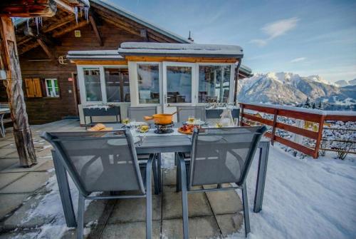 Una mesa y sillas en una terraza con una casa. en Chalet 4 personnes avec sauna, en Leysin