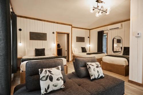 a hotel room with two beds and a couch at Motel Boutique Hygge - anciennement Aux Portes du Soleil in Baie-Saint-Paul