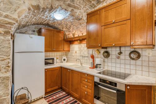 een keuken met houten kasten en een witte koelkast bij Medieval Villa Philoxenia in Kalamoti
