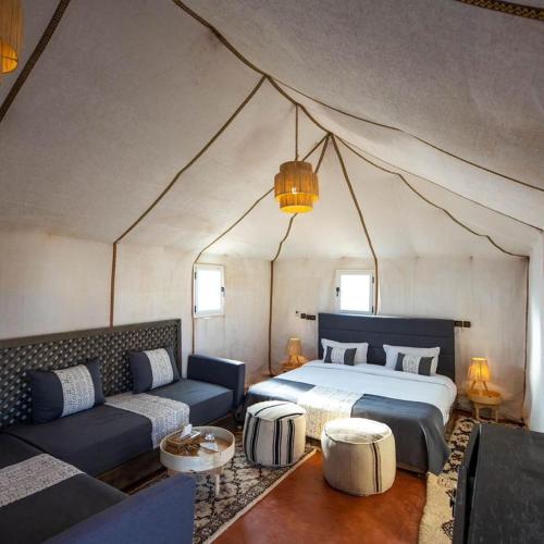 1 camera da letto in una tenda con letto e divano di Diamante Luxury Camp a Merzouga