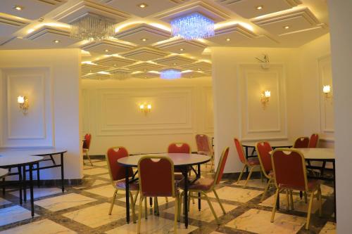 una sala da pranzo con tavoli, sedie e soffitto a cassettoni di تحت التجهيز a ‘Aţţān