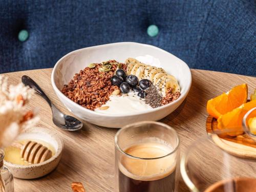 a bowl of granola and a bowl of fruit on a table at Mercure Aix-les-Bains Domaine de Marlioz Hôtel & Spa in Aix-les-Bains