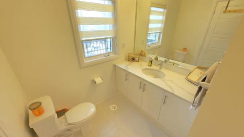 a white bathroom with a toilet and a sink at Nordic Three Brantford in Brantford