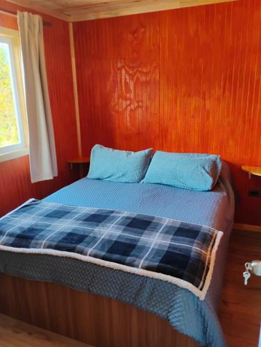 een bed in een kamer met een houten wand bij Cabaña colonia río sur in Puerto Varas