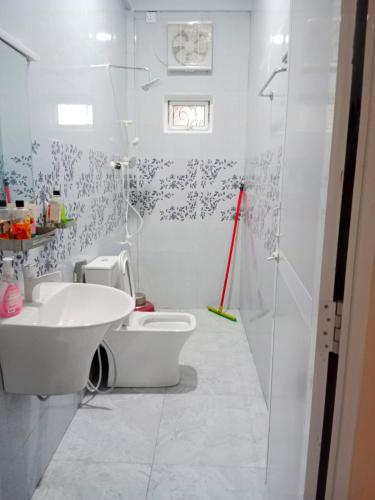 a white bathroom with a toilet and a sink at Velu House - 2-Room Apartment in Jaffna