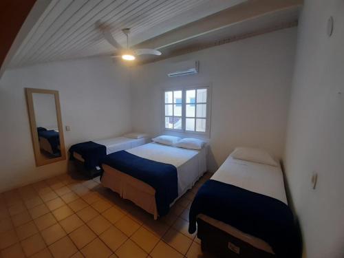um quarto com duas camas, um espelho e uma janela em Pousada Pantai Maresias em Maresias