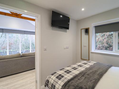 a bedroom with a bed and a couch and a television at Lodge at Nadur in Machynlleth