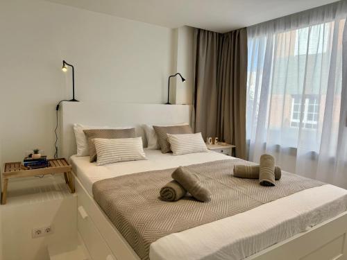 een witte slaapkamer met twee bedden en een raam bij Melenara Beach in Melenara