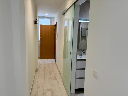 een gang met een badkamer met wastafel en spiegel bij Melenara Beach in Melenara