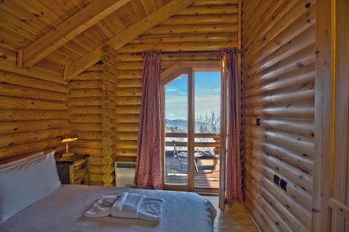 une chambre avec un lit et une grande fenêtre dans l'établissement Ξενώνας Σαν Παραμύθι, à Sinoikía Mési Trikálon