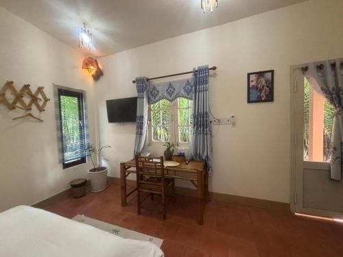 a bedroom with a desk and a bed and a table at Homestay Bentre Coco Lodge in Ben Tre