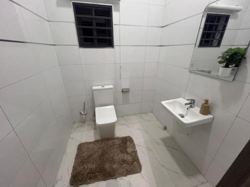 een witte badkamer met een wastafel en een toilet bij Akyamaa's Place Apartments in Accra
