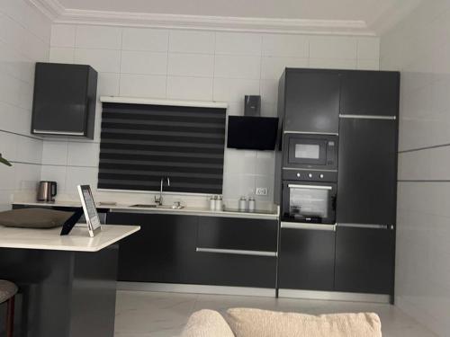 een keuken met zwarte kasten, een wastafel en een magnetron bij Akyamaa's Place Apartments in Accra