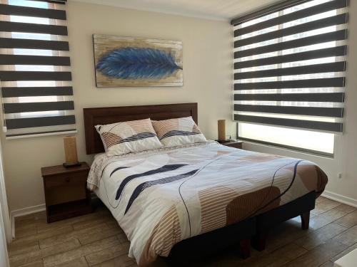 ein Schlafzimmer mit einem großen Bett mit zwei Fenstern in der Unterkunft Studio Cochrane in Santiago