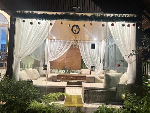 a living room with white curtains and couches at Thalia Home Măng Đen in Kon Plong