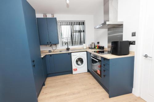 een keuken met blauwe kasten en een wasmachine bij Modern 3 bedroom home refurbished with parking in Wednesbury