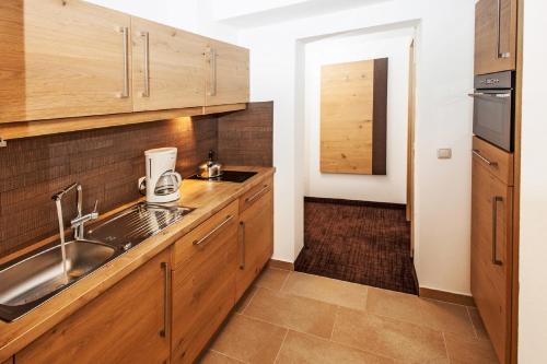 a kitchen with wooden cabinets and a sink at Landhaus Gappmaier in Saalbach Hinterglemm