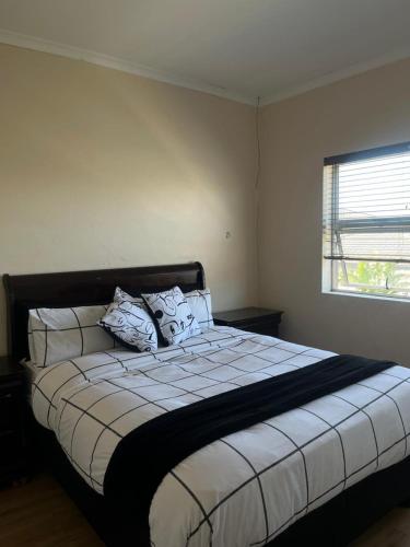 a bedroom with a bed with white sheets and a window at Sleep easy at Peperboom in Kuilsrivier