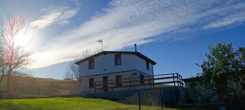 una piccola casa bianca su una collina con una recinzione di La Tadorna a Suances