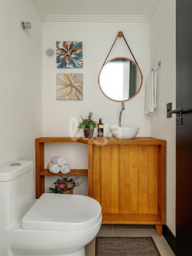 a bathroom with a white toilet and a mirror at LUGA Relax House with Jacuzzi in Palhoça