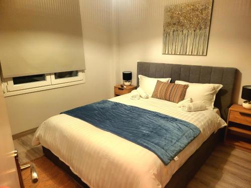 ein Schlafzimmer mit einem großen Bett und einer blauen Decke in der Unterkunft Helios Houses - Ioannina in Ioannina
