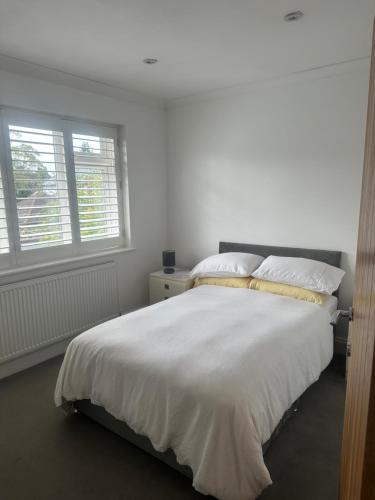 a bedroom with a large white bed with two windows at Mayfield guest rooms in Bromley