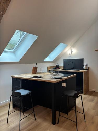 a kitchen with a black island with two stools at Résidence ARTHUS Thamarys in Pierrefonds