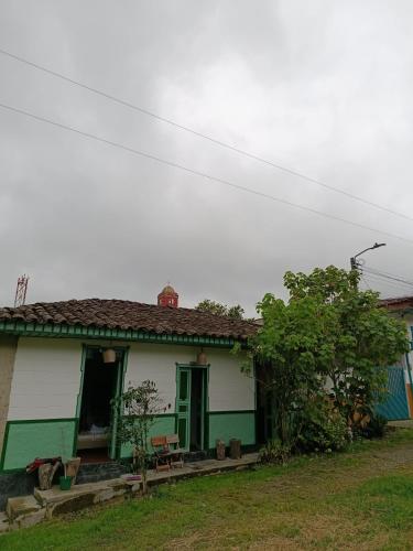 Koniminto Hostal في Pijao: بيت اخضر وبيض مع باب اخضر