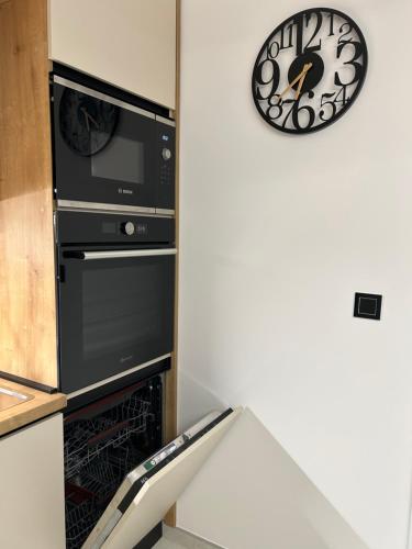 een keuken met een oven en een klok aan de muur bij Apartman MARIA 3 in Kutina