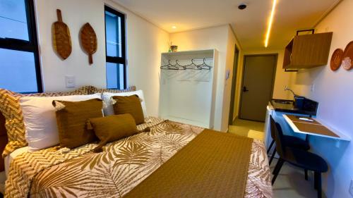 a bedroom with a bed with pillows and a desk at Hit Cabo Branco Flat Aconchego a 30 metros do mar in João Pessoa