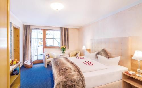 a hotel room with a large white bed and a window at Hotel Alpenkönigin - ALPINE LUXURY in See