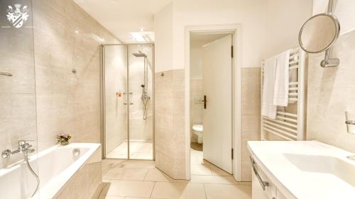 een badkamer met een douche, een bad en een wastafel bij Hotel & Spa Wasserschloss Westerburg in Westerburg