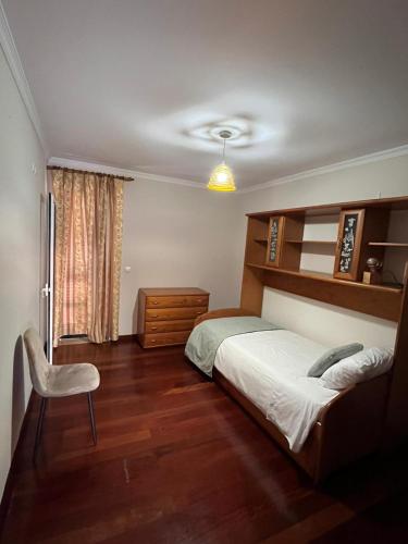 a bedroom with a bed and a chair and a window at Casa Do Arco - Machico Centre with Private Balconies and Parking in Machico